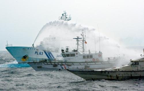 臺灣“海巡署”的巡邏船（中）在掩護保釣船“全家?！碧枺ㄓ遥┒惚苋毡竞Ｉ媳０矎d巡視船的水炮攻擊。